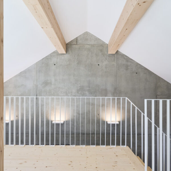 Dachgeschoss-Raum mit Blick auf Giebel-Betonwand und Treppengeländer