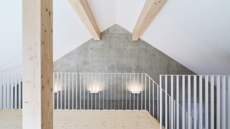 Dachgeschoss-Raum mit Blick auf Giebel-Betonwand und Treppengeländer