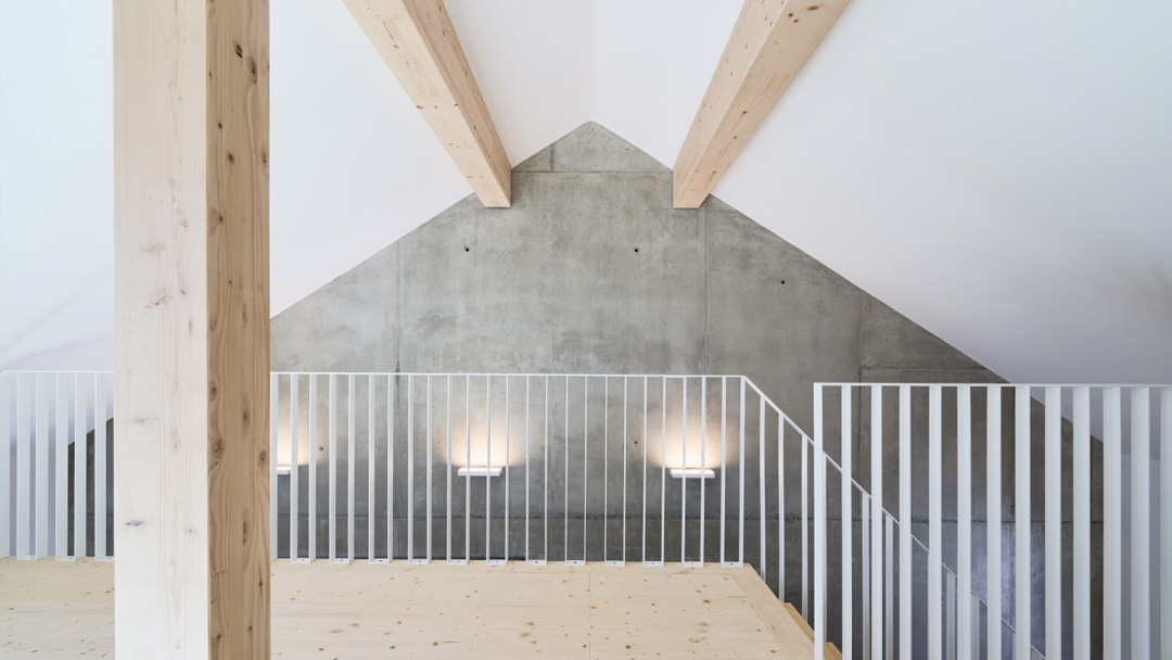 Dachgeschoss-Raum mit Blick auf Giebel-Betonwand und Treppengeländer