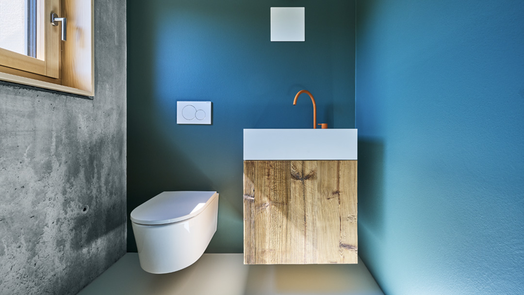 WC mit modernem Waschtisch und orangefarbener Armatur